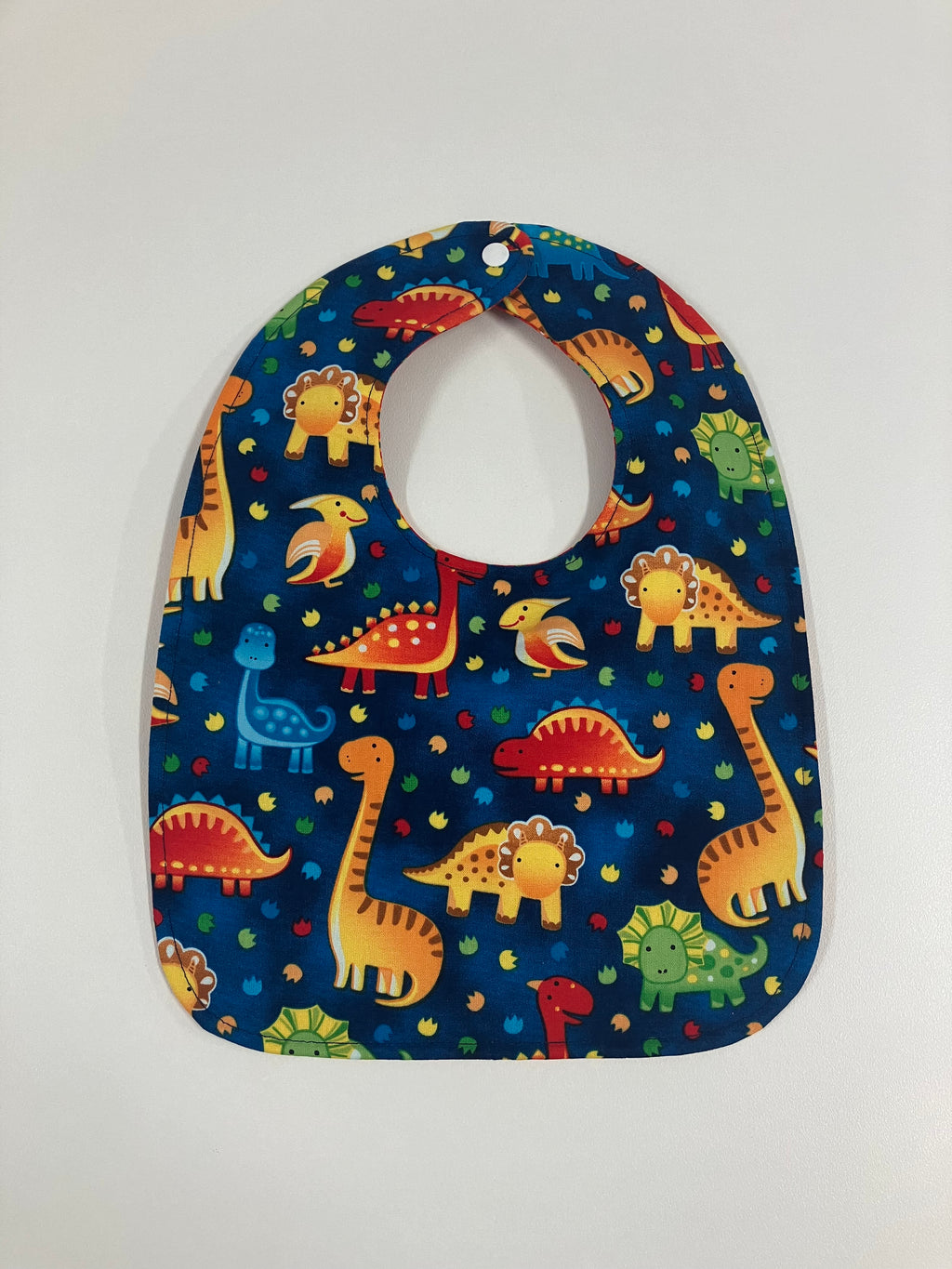Reversible Bib – Blue Dinosaurs / Red with Spots
